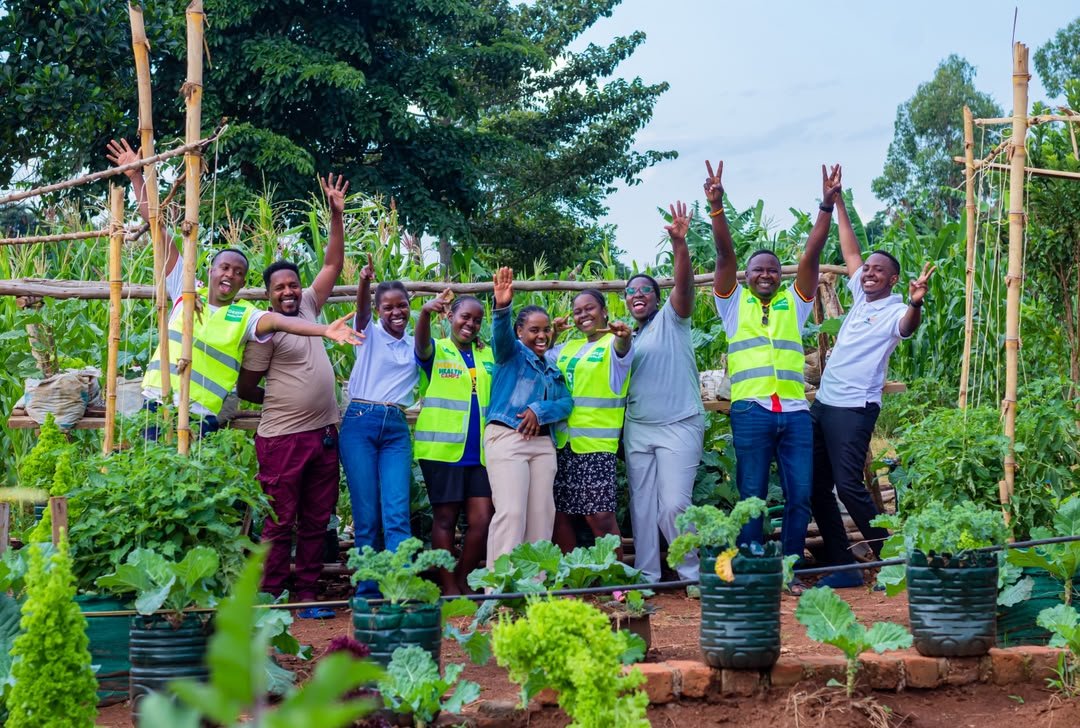 The Hands for You team celebrating in a thriving recycled-bottle kitchen garden
